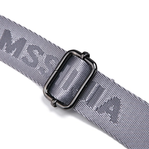 Detail of adjustable metal buckle on gray woven shoulder strap with letter pattern