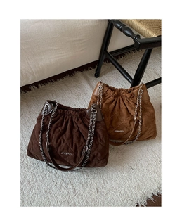 Detail of dark coffee and camel suede quilted bucket bags with stylish metal chain straps