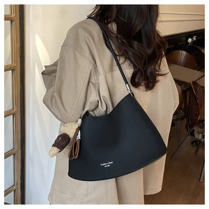 Detail of black leather crescent underarm bag featuring a cute brown monkey charm
