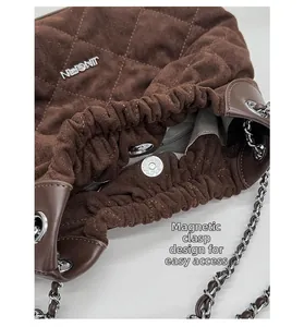 Detail of dark brown quilted suede bucket bag showing magnetic closure and chain strap
