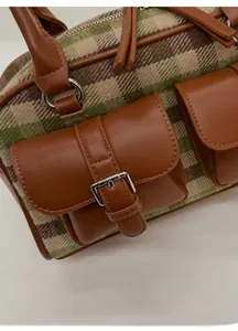 Detail of green plaid Boston bag with brown PU leather trim and metal buckles