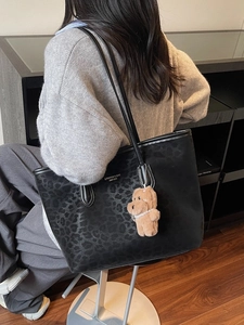 Chic black leopard print tote bag with bear charm shown on a female model