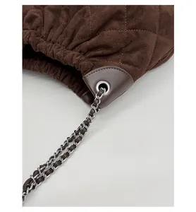 Detailed close-up of brown quilted suede bucket bag featuring drawstring and chain strap