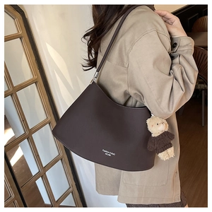 Detail view of coffee brown hobo bag with teddy bear charm and fashion logo print