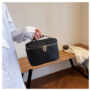 Dettaglio della trousse nera glitterata con doppia zip dorata e manico superiore robusto