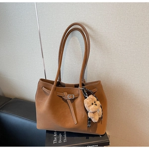 Dettaglio borsa tote in pelle marrone con fibbia argento e ciondolo a orsetto