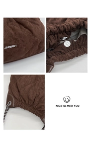 Close-up of quilted dark brown suede bucket bag with silver chain strap and metal logo