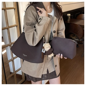 Detail of dark brown leather underarm bag set with bear charm and fashion lettering