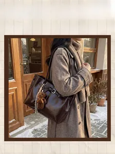 Detail of dark brown glossy tote bag with teddy bear charm in a winter outdoor setting