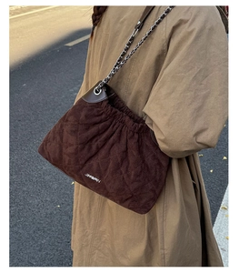 Close-up of brown quilted bucket bag with silver metal chain strap and drawstring detail