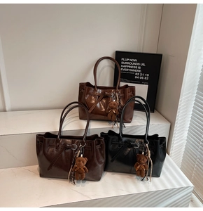 Three vintage tote bags in black and brown finishes with plush bear charms on marble