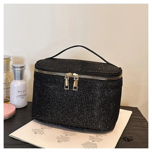Dettaglio del beauty case in paillettes nere con doppia chiusura a zip in metallo oro