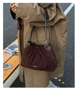 Detail of dark brown quilted bucket bag with chain strap and drawstring closure