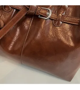 Close-up of caramel brown tote bag featuring glossy oil wax texture and silver metal buckle