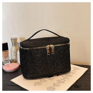 Dettaglio della trousse nera glitterata con doppia cerniera dorata e manico