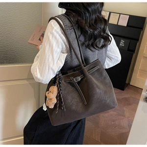 Borsa tote in camoscio marrone con fibbia in metallo e ciondolo a orsetto su una modella