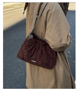 Close-up of brown quilted suede bucket bag with metal chain strap and drawstring closure