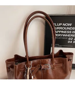 Close-up of a large dark brown tote bag with glossy leather finish and silver buckles