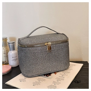 Dettaglio di una trousse per trucchi grigia glitterata con cerniera dorata