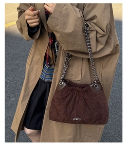 Detail of dark brown quilted suede shoulder bag with silver chain strap and drawstring design