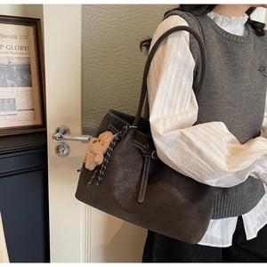 Dettaglio borsa tote in pelle scamosciata marrone scuro con cuciture e orsetto