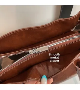 Close-up of smooth metal zipper and polished brown leather texture on a tote bag