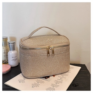 Dettaglio della borsa per cosmetici champagne glitterata con doppia cerniera e riflessi lucidi