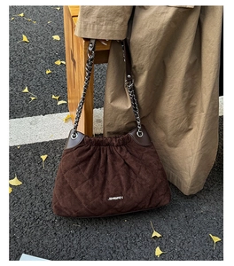 Detail of coffee quilted bucket bag with silver chain strap and velvet texture