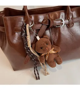 Detail of cute plush bear charm with Love ribbon on dark brown leather tote bag