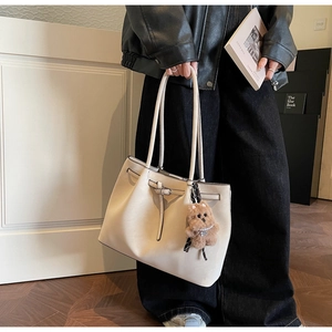 Dettaglio della borsa tote in pelle bianco crema con fibbia argento e orsetto peluche