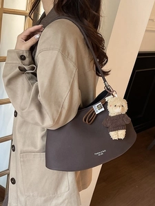Chic coffee brown leather hobo shoulder bag with cute teddy bear charm in a cafe setting
