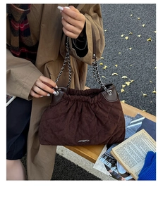 Detail of dark brown quilted suede bucket bag with silver chain strap on autumn background