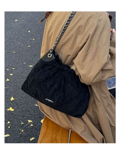 Quilted black bucket bag detail with silver chain strap shown in autumn street setting