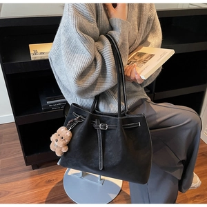 Dettaglio borsa tote in pelle nera con cuciture bianche a contrasto e ciondolo orsetto