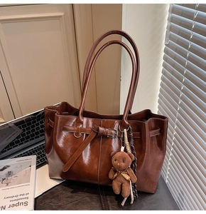 Detail of vintage matte brown tote bag with decorative buckle and plush bear charm