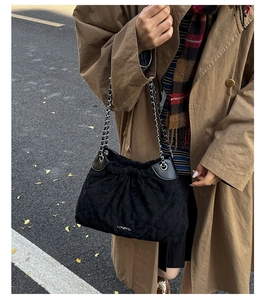 Close-up of black quilted suede bucket bag with drawstring and silver chain strap