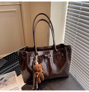 Deep brown matte tote bag with decorative buckle and cute plush bear charm detail