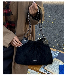 Detail of black quilted bucket bag featuring drawstring closure and silver chain strap