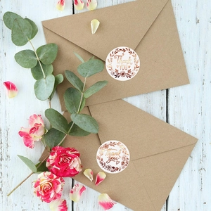 Round white Thank You stickers with rose gold foil floral design on kraft envelopes