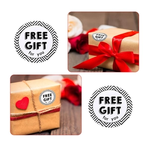 Détail des autocollants Free Gift For You sur boîte cadeau kraft avec ruban rouge