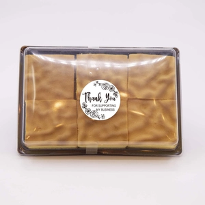 Top view of six pieces of golden sponge cake in a transparent box with Thank You stickers