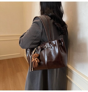 Detail of vintage brown tote bag with smooth texture and cute plush bear accessory