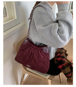 Detail of burgundy quilted bucket bag with silver chain strap and velvet-like finish