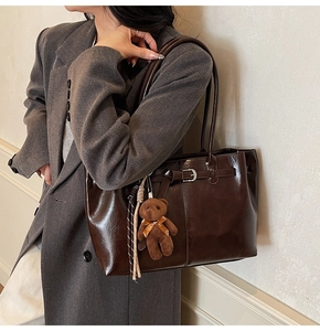Detail of vintage oil wax leather tote bag with silver buckle and brown bear charm