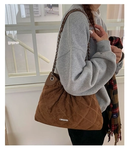 Close-up of brown quilted suede bucket bag with silver chain strap and metal logo