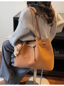 Borsa tote in camoscio marrone con fibbia e ciondolo a orsetto indossata dal modello