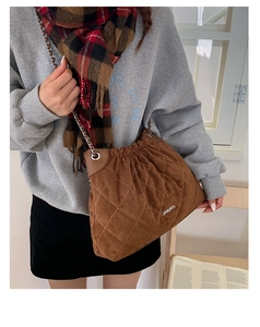 Brown quilted suede bucket bag with chain strap shown on a model in autumn outfit