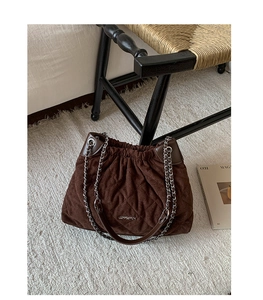 Detailed texture of brown quilted bucket bag with silver chain and JINGPIN metal logo