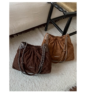 Close-up of diamond quilted suede bucket bags with metal chain straps and drawstring