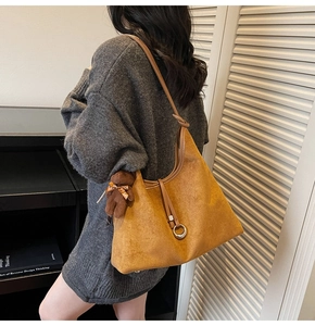 Detail of tan suede tote bag with slim straps and a cute plush brown bear keychain